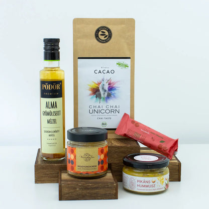 A képen több termék található, fehér háttérrel. Két üveg, egy ecetes üveg és egy cseresznyeszínű szelet és egy drapp színű kakaópor. 