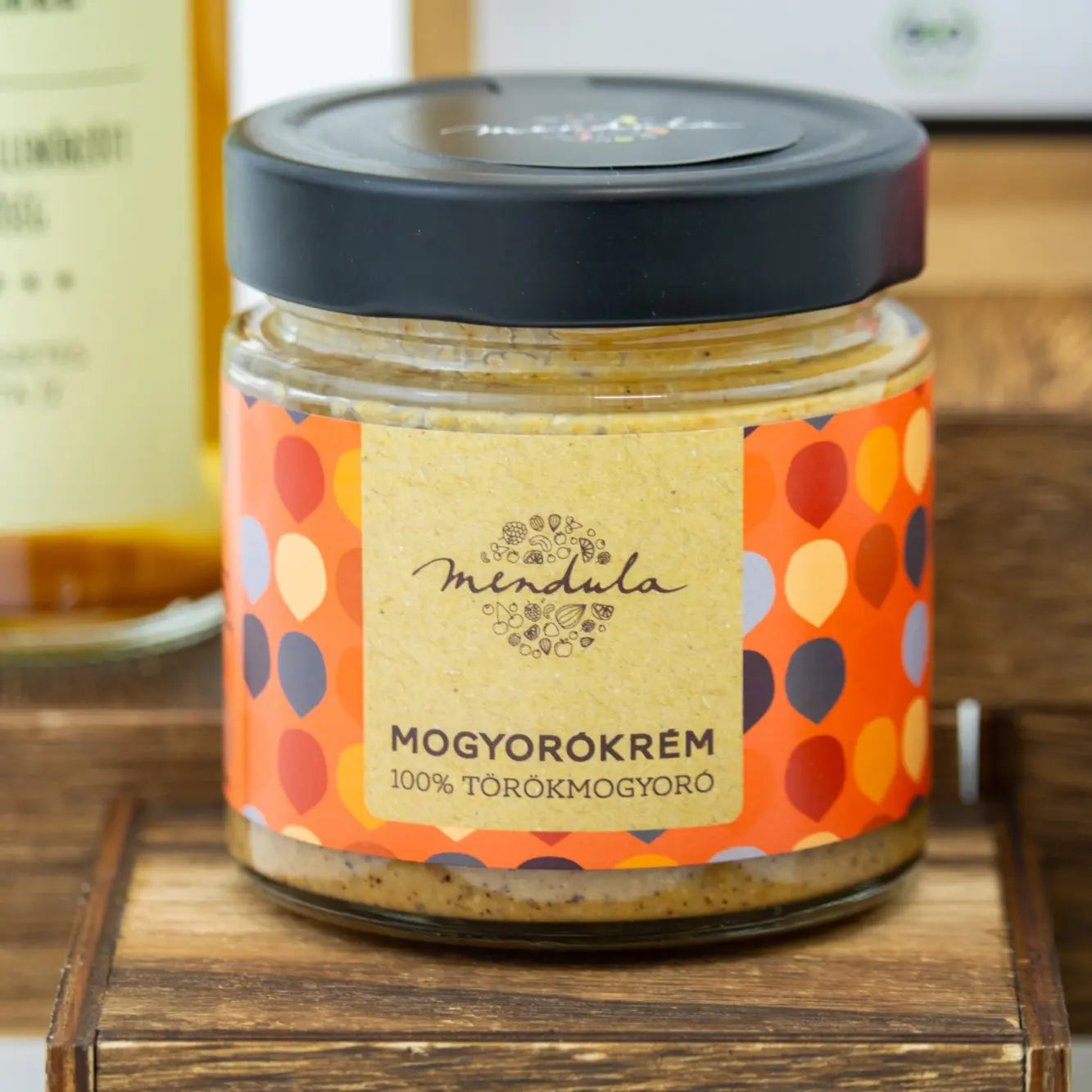 A képen a Mendual mogyorókréem látható, amelynek fekete a kupakja. Az üvegben a finomra őrölt mogyorószemcsék találhatóak. Az üveg csomagolása nagyon színes. 