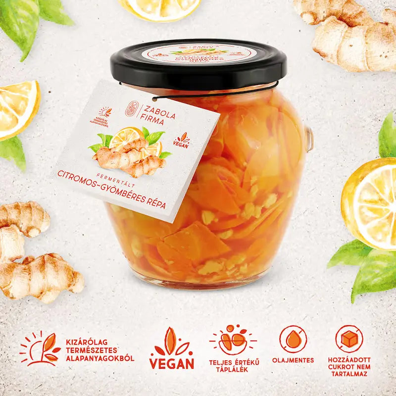 Az üvegbe citromos- gyömbéres répa van, látszanak a gyömbér darabkák és a szépen felvágott répaszeltek. Az üveg körül gyömbér, citrom és répa darabkák találhatóak. 