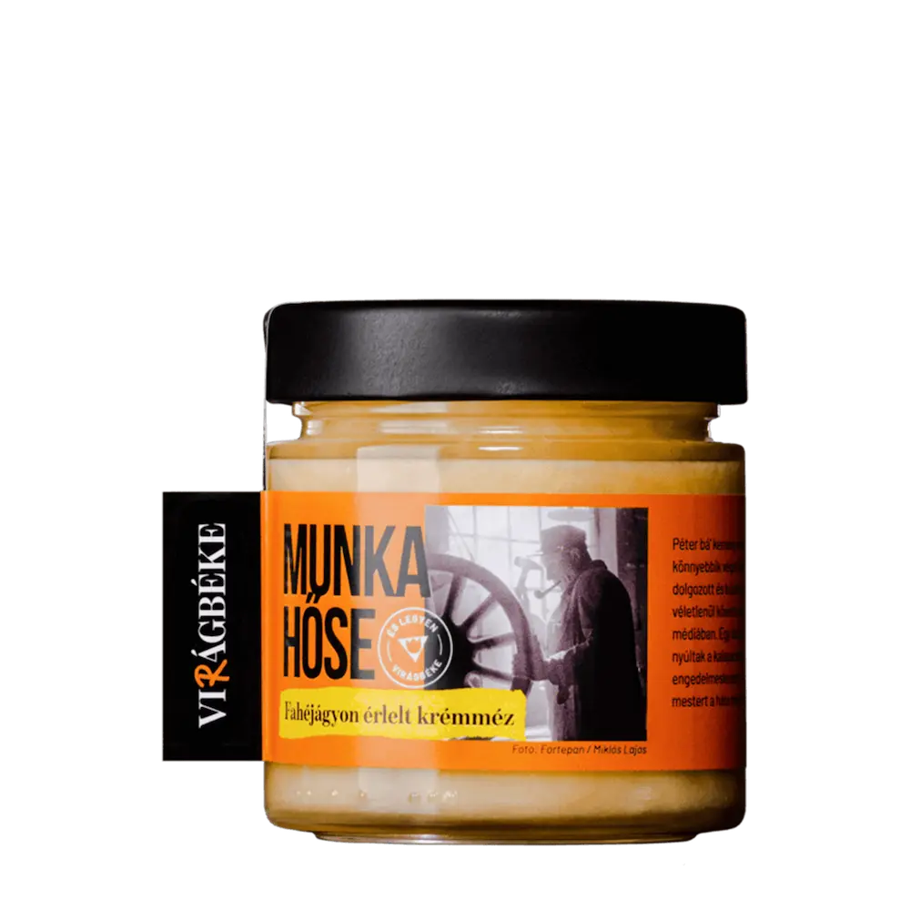 A Virágbéke "Munka hűse" fahéjágyon érlelt krémméze látható. A méz krém színű a címke narancssárga. Egy dolgozó embert lehet látni a képen. 
