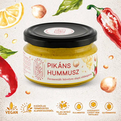 Pikáns hummusz a Lardershelf kínálatából. Az üveg lapos, fekete kupakkal van lezárva. A hummusz arany színű, a fehér címékén csicseriborsó, citrom és paprika grafikája látható. Az üveg körül szintén ezeknek a növényeknek a grafikája van felvázolva. 